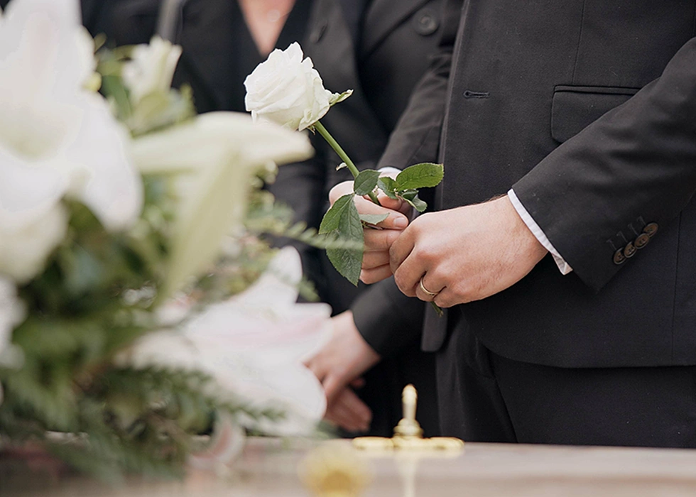 Ein Mann mit einer weißen Rose bei einer Trauerfeier auf dem Friedhof. Ein Mann mit einer weißen Rose bei einer Trauerfeier auf dem Friedhof.